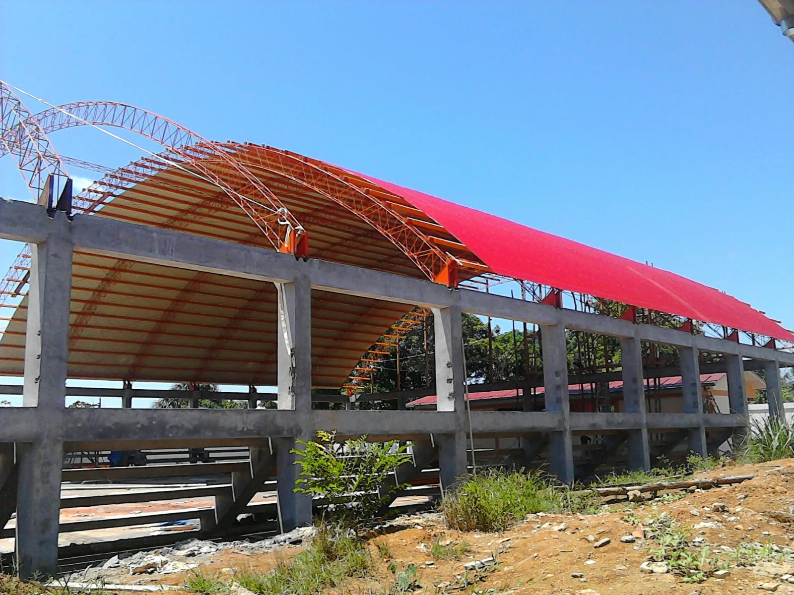 Cobertura curva con estructura metálica y apoyos de concreto